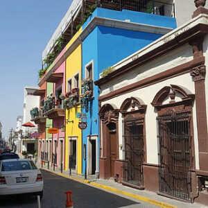 Buildings painted in green, pink, yellow and blue on a street.