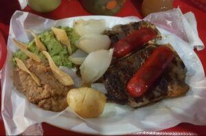 Carne asada with Mexican sausage, refried beans, guacamole, grilled onion, chips and potato.