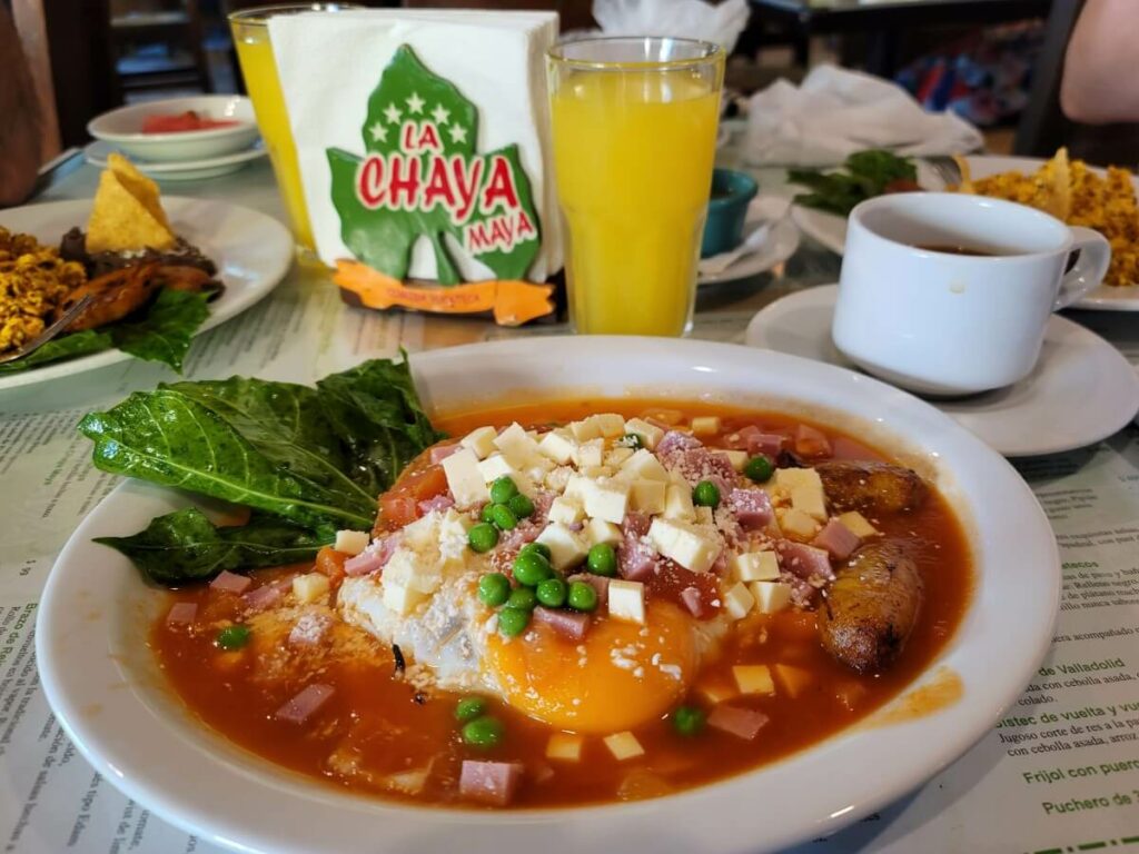 Eggs with red sauce, cheese cubes, beans, and plantain.