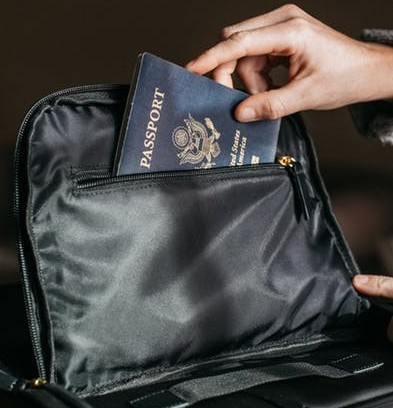A person putting his passport inside his bag.