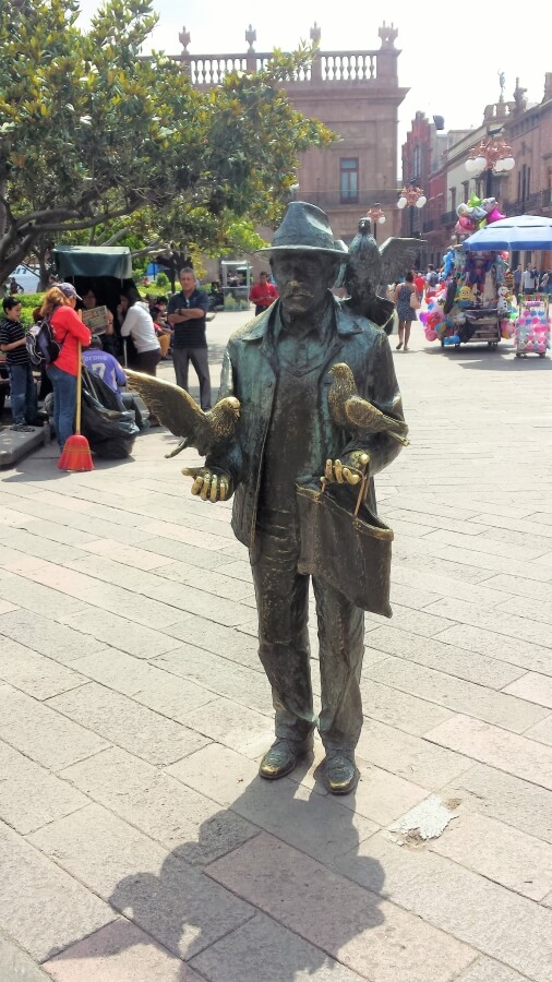 Statue of a man feeding doves.