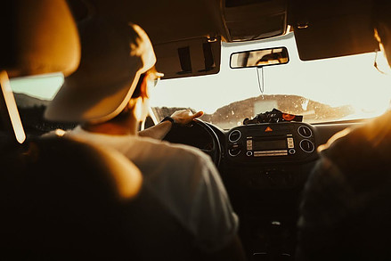 Guy driving against the sun and wearing a hat.