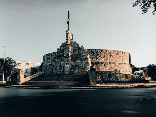 Monument with Mayan motifs and the Mexican flag on top.