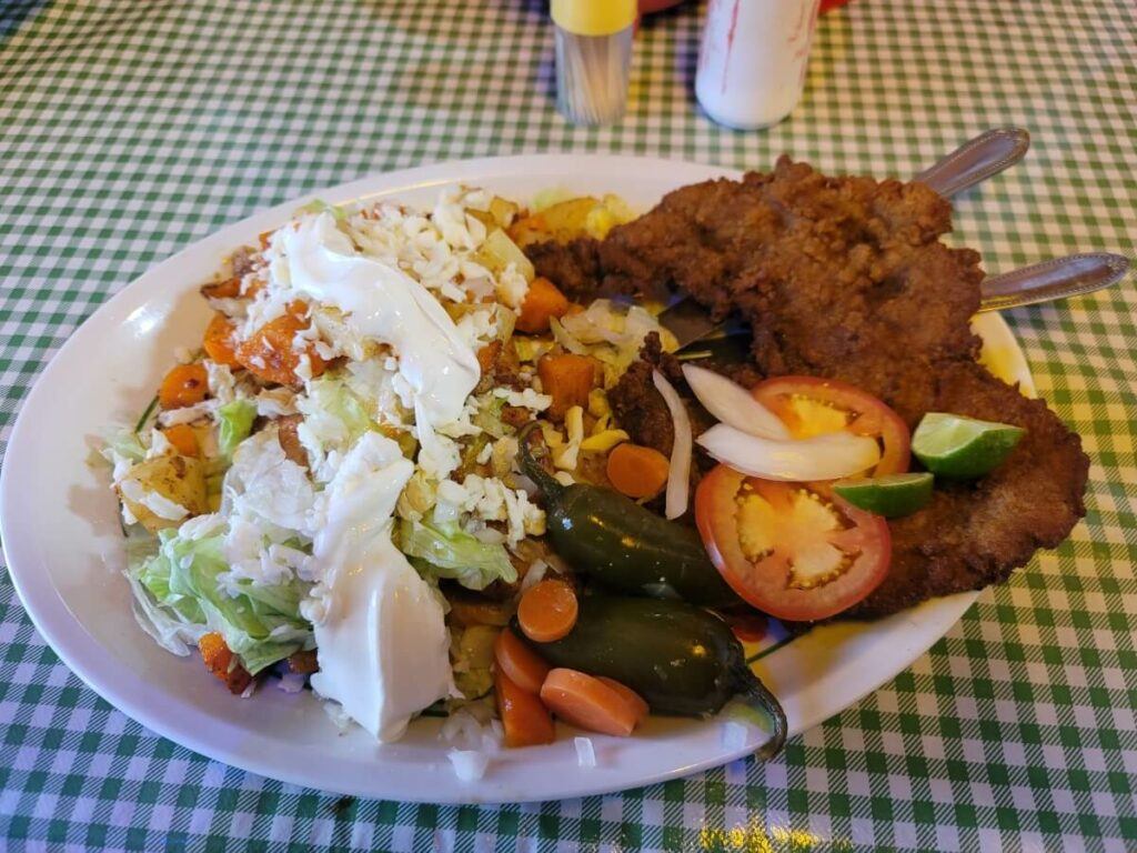 A dish of enchiladas with potatoes, vegetables, and meat.