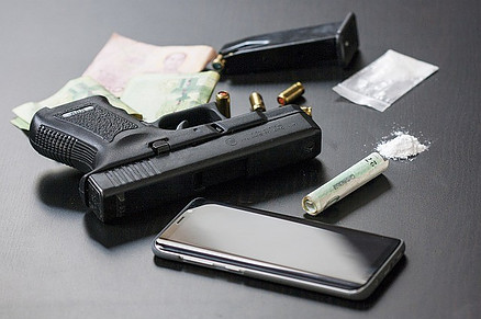 Black firearm, cellphone, drugs and money.