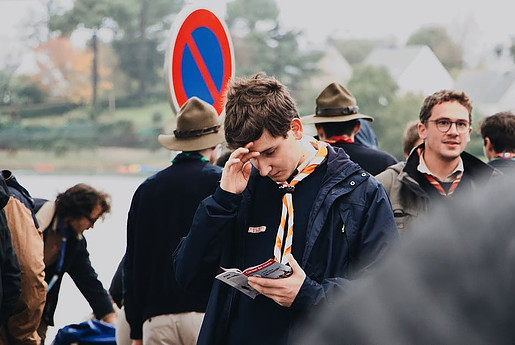 Several people in a group with a young man in the center touching his forehead and holding a paper in his other hand.