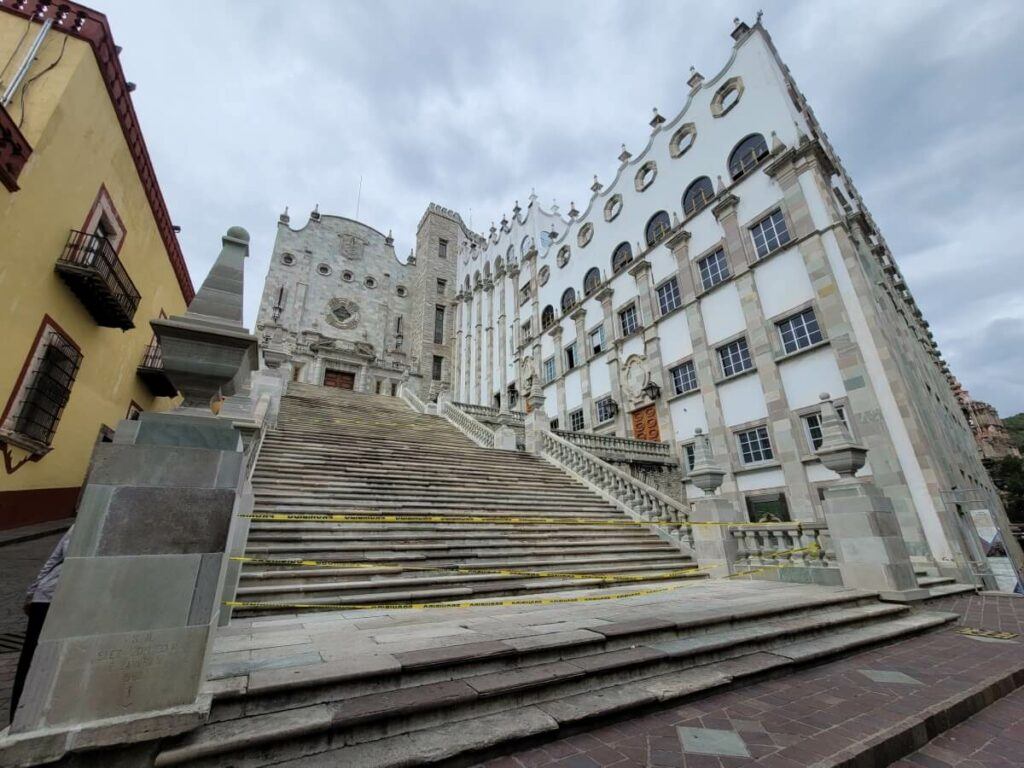 A gray bulding made of quarry with a long stairway.