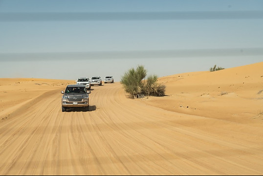 Four vans in a row driving in the desert.