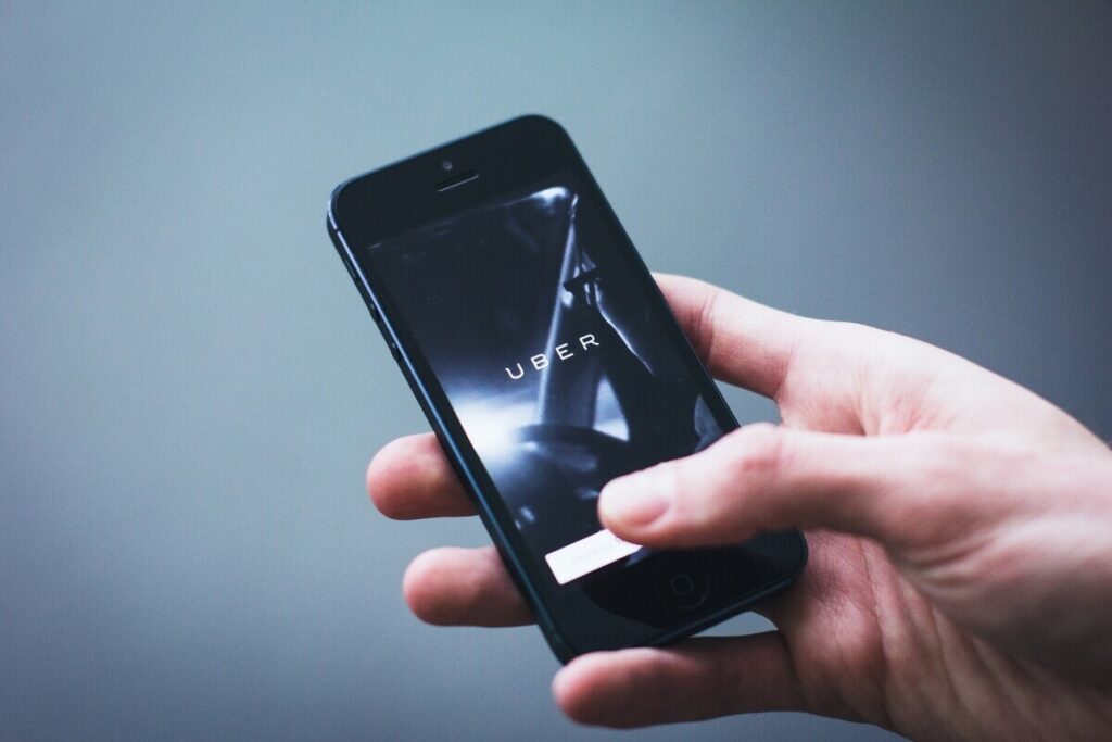 A hand holding a smartphone with the uber app on it.