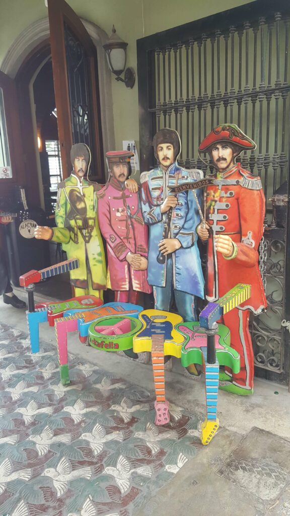 Colorful bench made of guitars and the Beatles in the back.