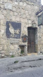 Old stone building with a rooster sign at the entrance.