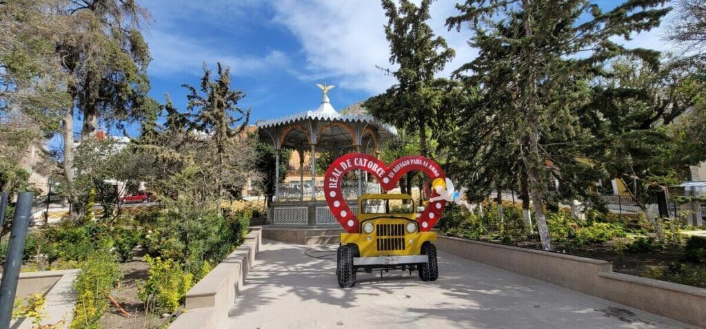 A plaza with gardens and an iron kiosk in the center.