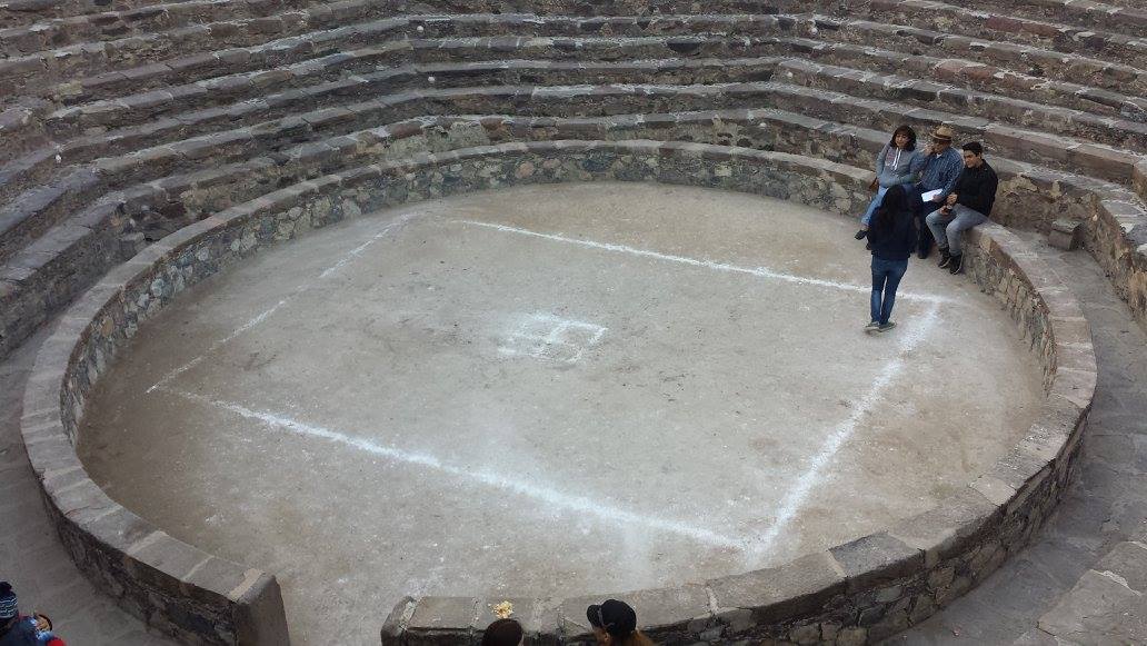 Four people seated in a cockfighting ring.