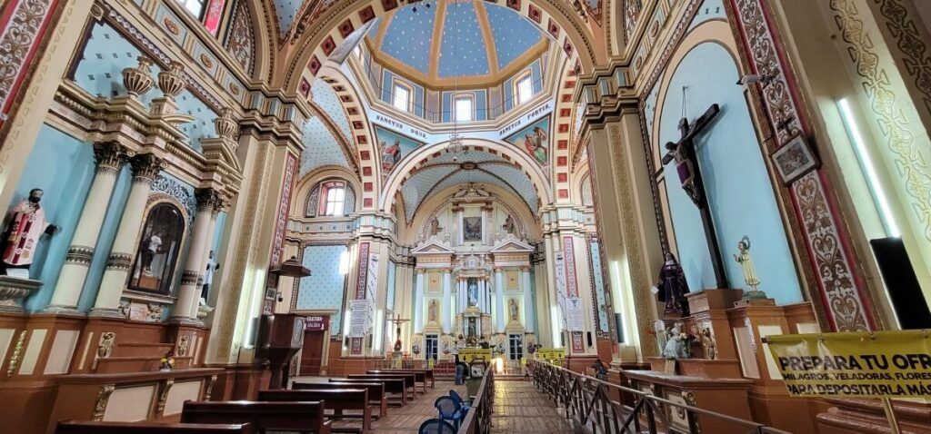 Interior of a Catholic church with light blue walls and various saints.