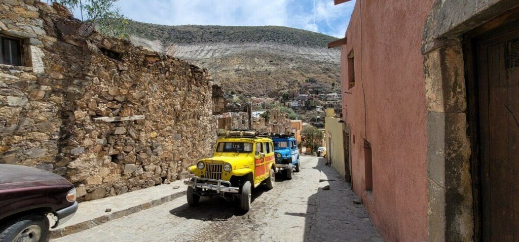 A yellow and a blue jeep on the street.