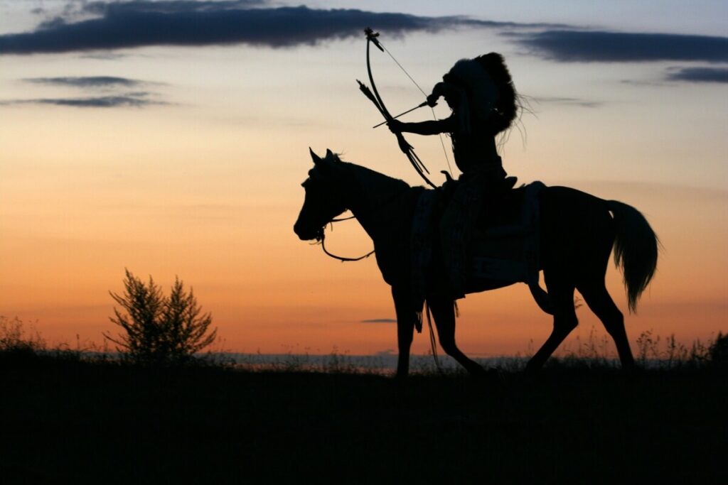 Apache riding a horse and holding a bow in his hand.