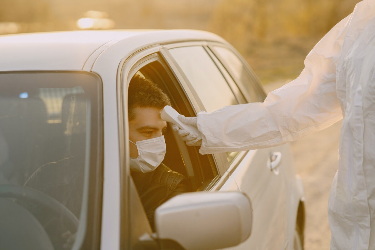 Man wearing a face mask and having his temperature checked.