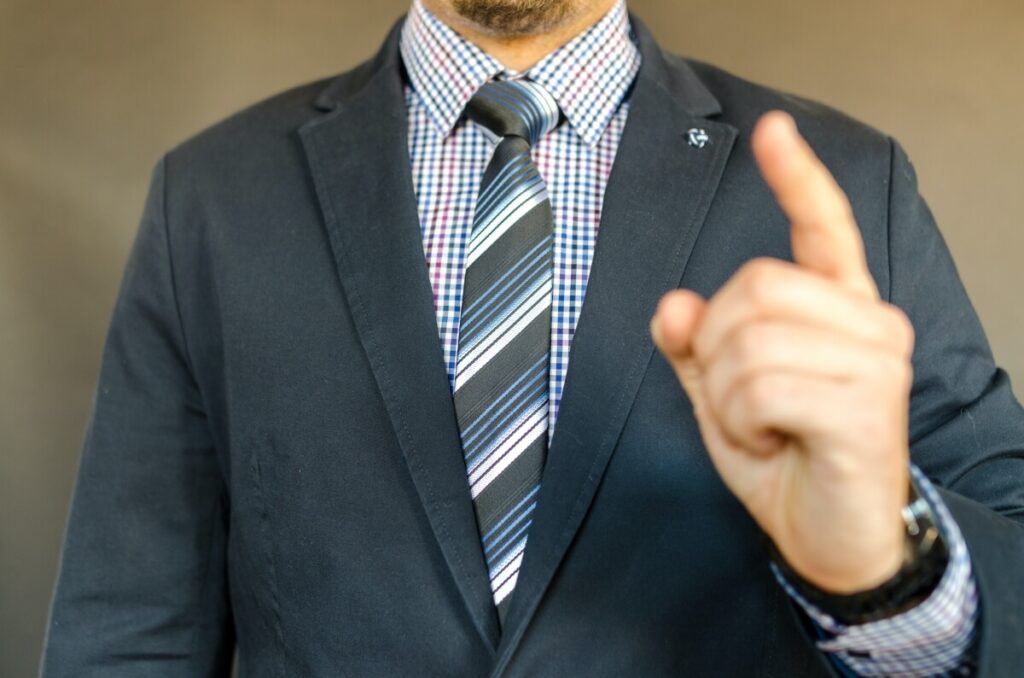 Man in suit pointing with his left hand.