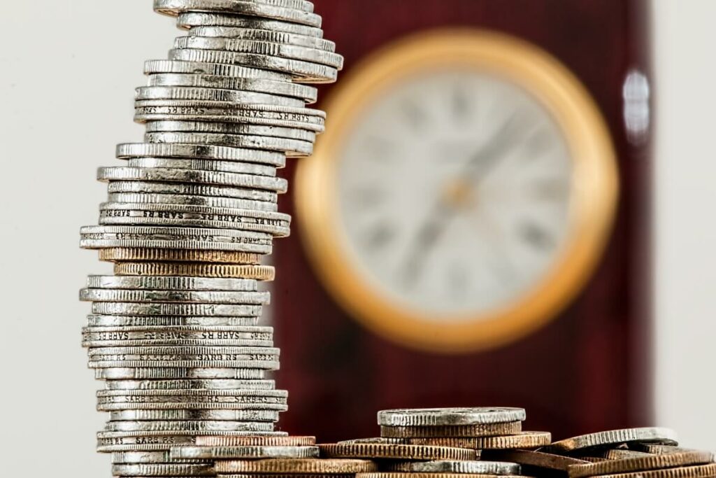 Coins stacked up and clock behind them.