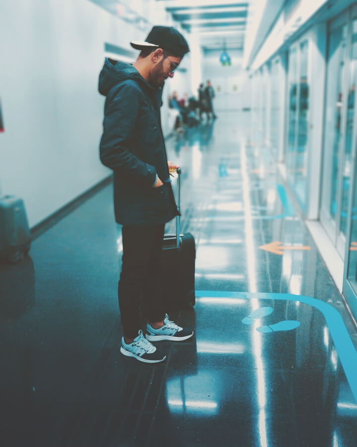 Young man waiting at the airport with his suitcase.