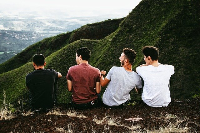 Four young men seated in the mountains.