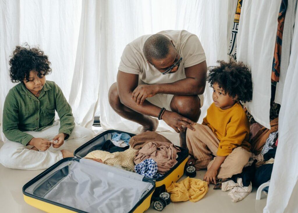 African American with his kids packing up a suitcase.