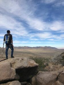 Young man standing on top of a rock and looking at the desert