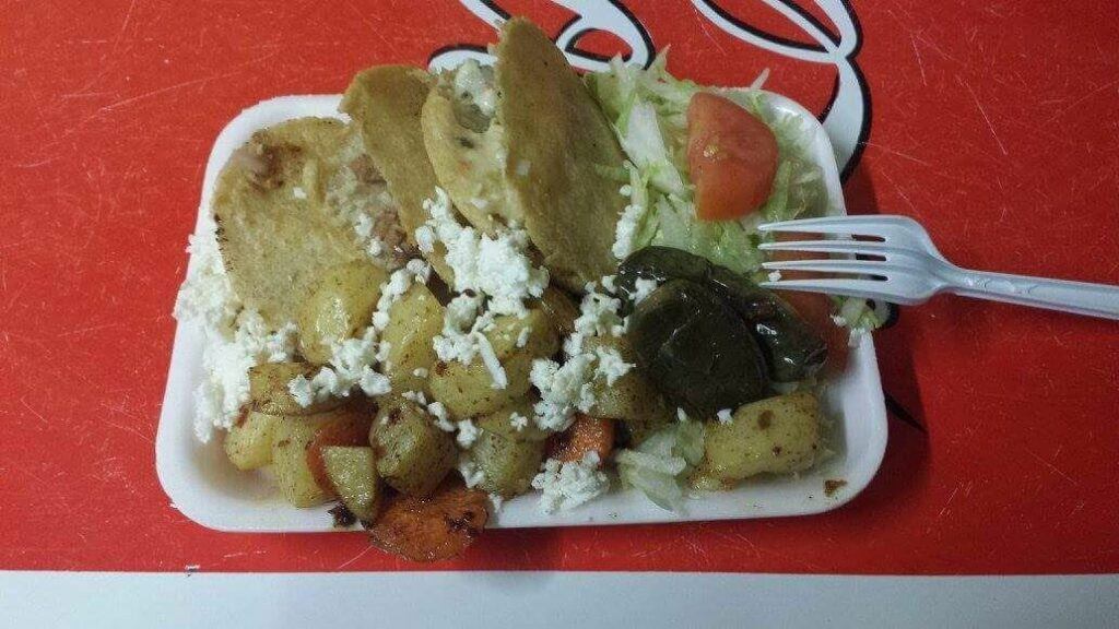 Two cheese gorditas with potatoes, lettuce, tomato, and a jalapeno pepper.