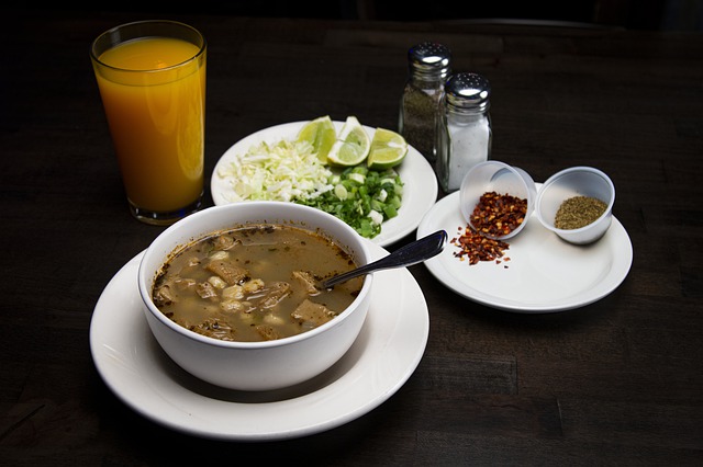 A bowl of menudo with lime, chilin and onion.