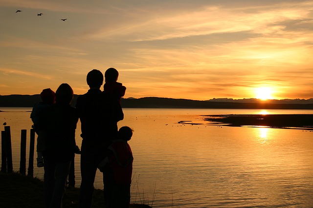 Family silhouettes looking at the sunset.