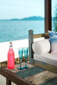 A bottle of wine and two glasses with the sea in the background.