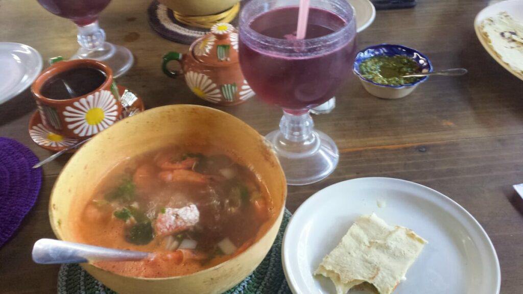 A kind of soup with fish, shrimp, and vegetables accompanied by hibiscus tea.