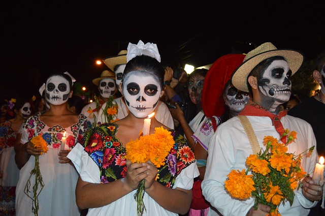 Several people dressed in traditional white clothes and holding marigolds and candles in their hands.