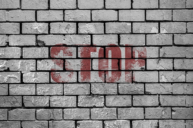 The word stop written in red letters on a gray brick wall.