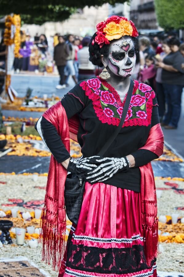 Woman wearing a black and pink dress and characterized as a catrina.