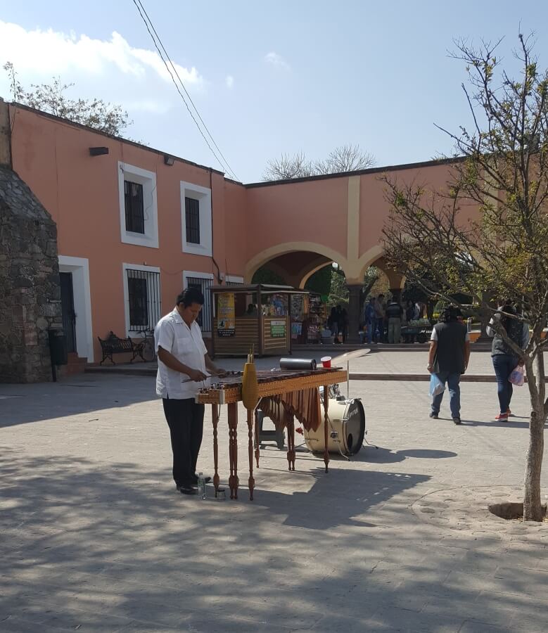 A man playing the marimba in the middle of a plaza.