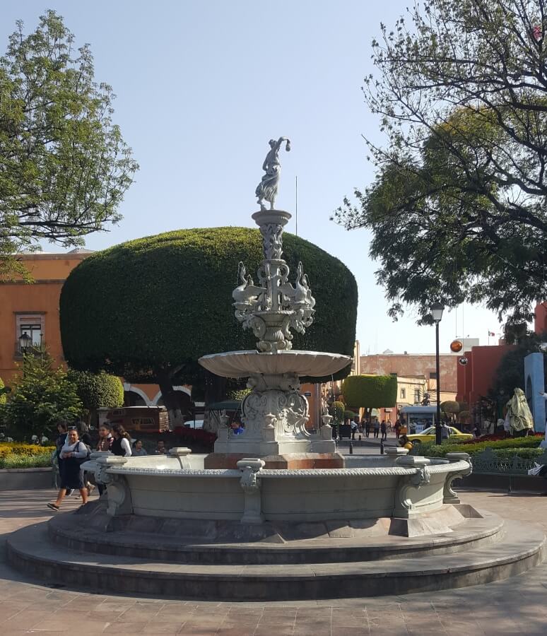 A white fountain with the statue of a woman on top.