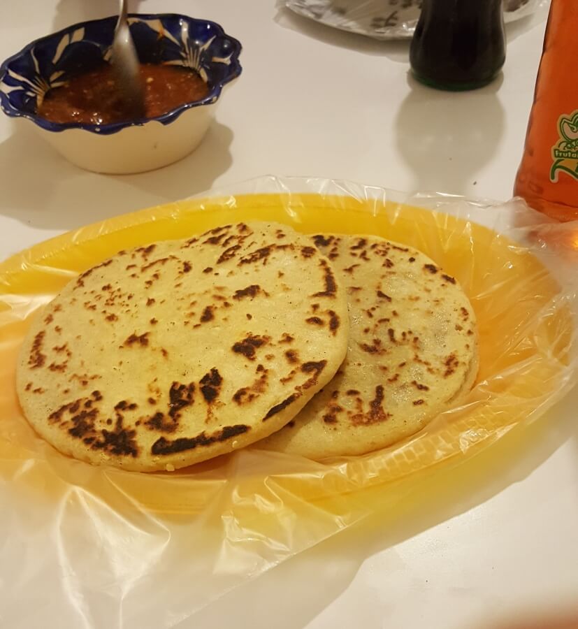 Two Mexican gorditas with salsa on the side.