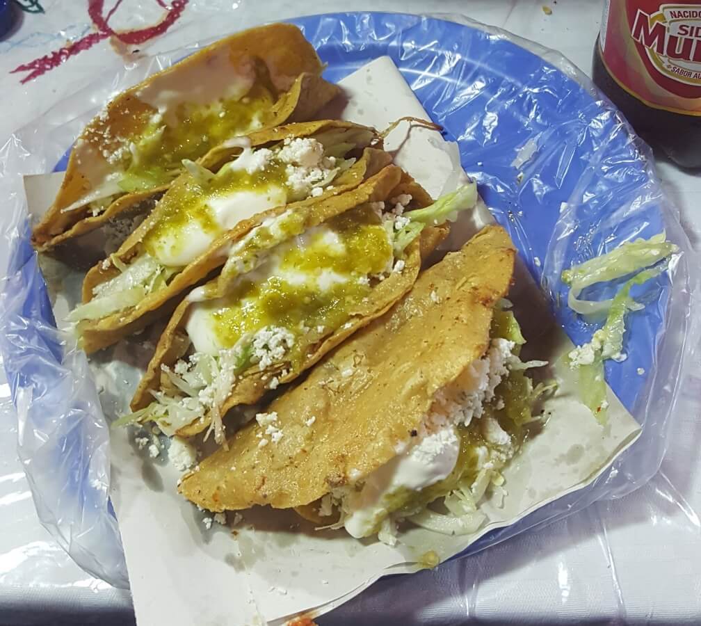 Tacos with different fillings, lettuce, cheese, and cream.