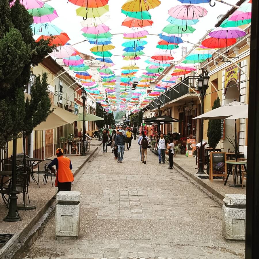 A street with lots of colorful umbrellas over it.