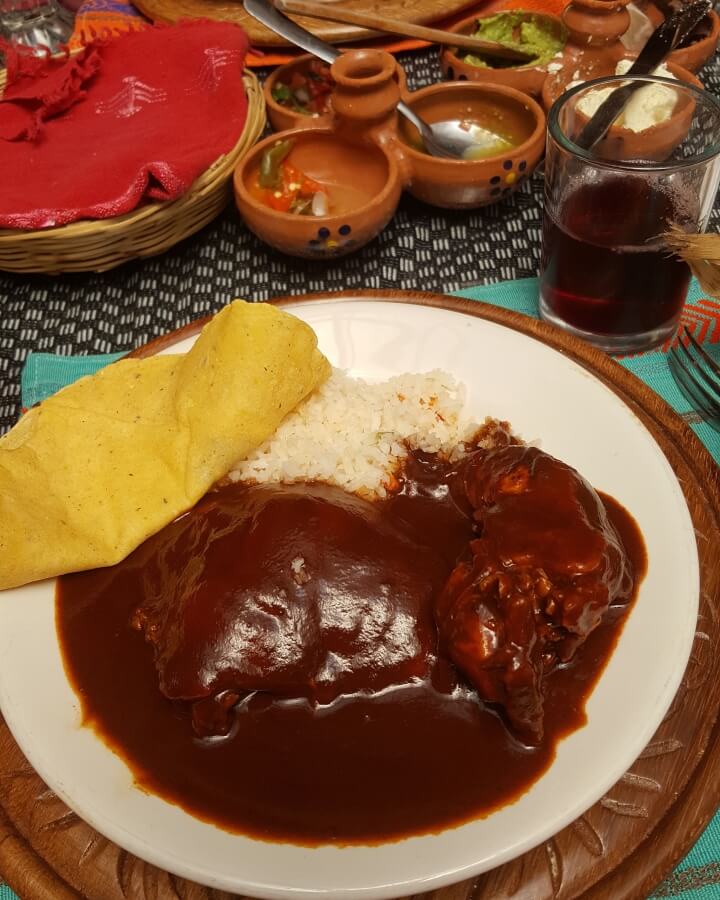 A plate with mole, rice, and a tortilla.