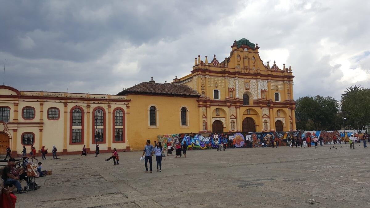 Yellow cathedral with a fence with graffiti on it.