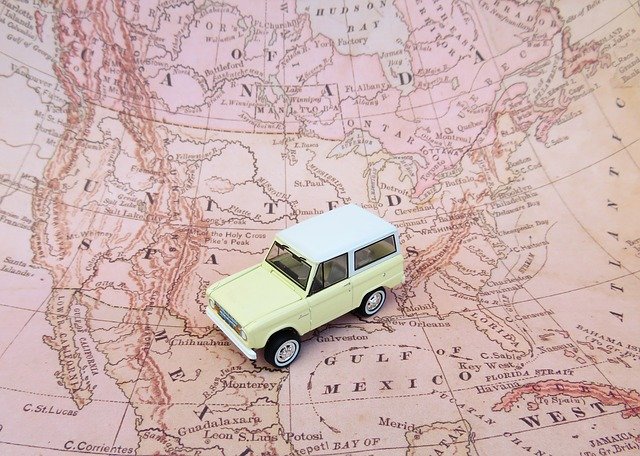 A tan car traveling over a pink map.