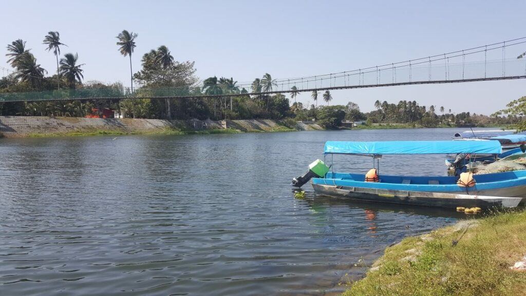 A boat by the side of a river and a bridge in the back.