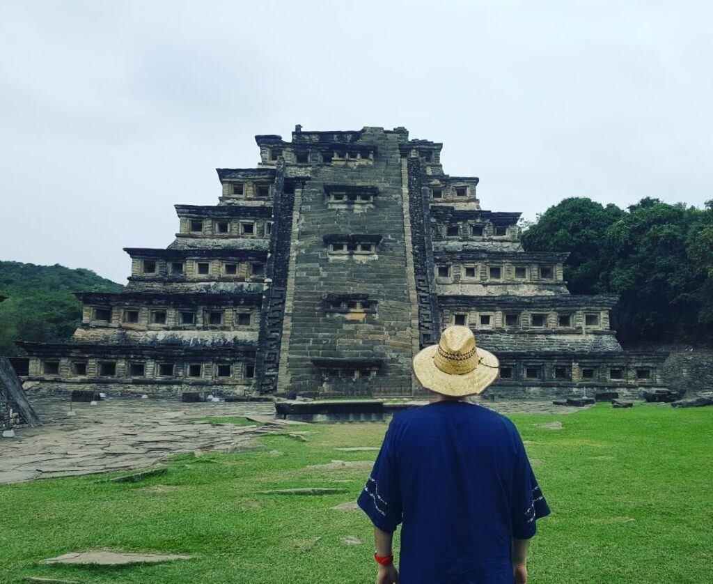 A young man dressed in blue looking at a pyramid.