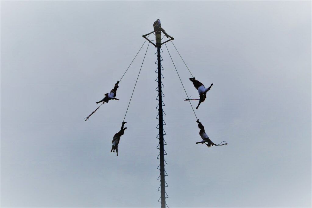 Four men tied by their feet and suspended in the air.