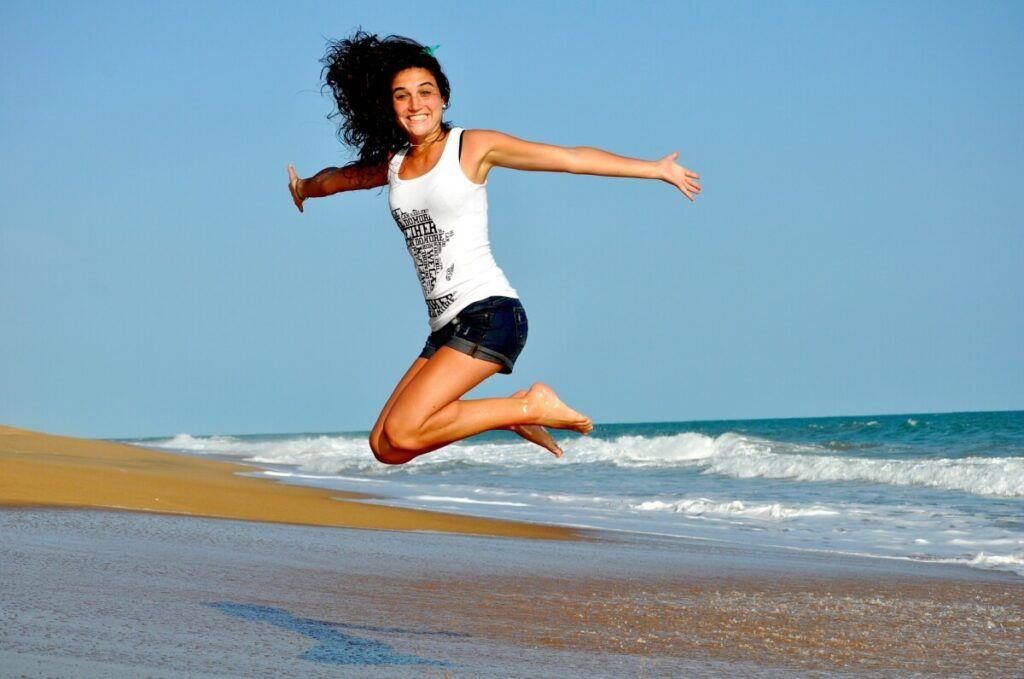 A happy woman jumping at the beach.