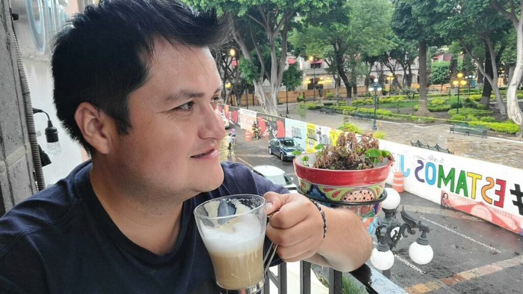 A man holding a cup of coffee and looking at the street.