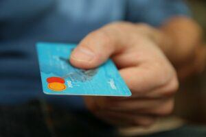 A hand holding a blue debit card.