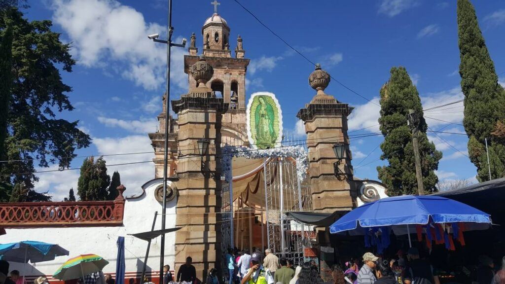 Facade of an old church with a giant image of the Virgin of Guadalupe.